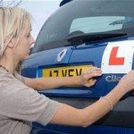 Woman putting learner plates on blue Renault Clio vehicle